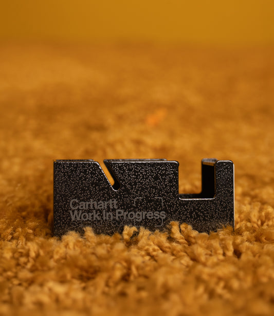 Black Carhartt WIP Penco tape dispenser standing on a textured ochre carpet