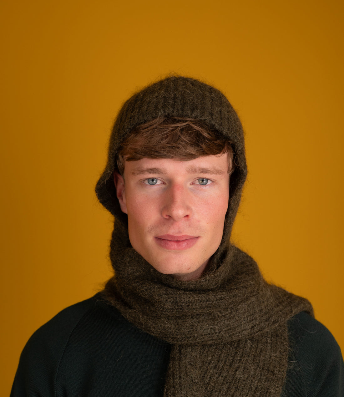 Model wearing the Bisa Hooded Scarf in sage with the hood up and scarf around the neck