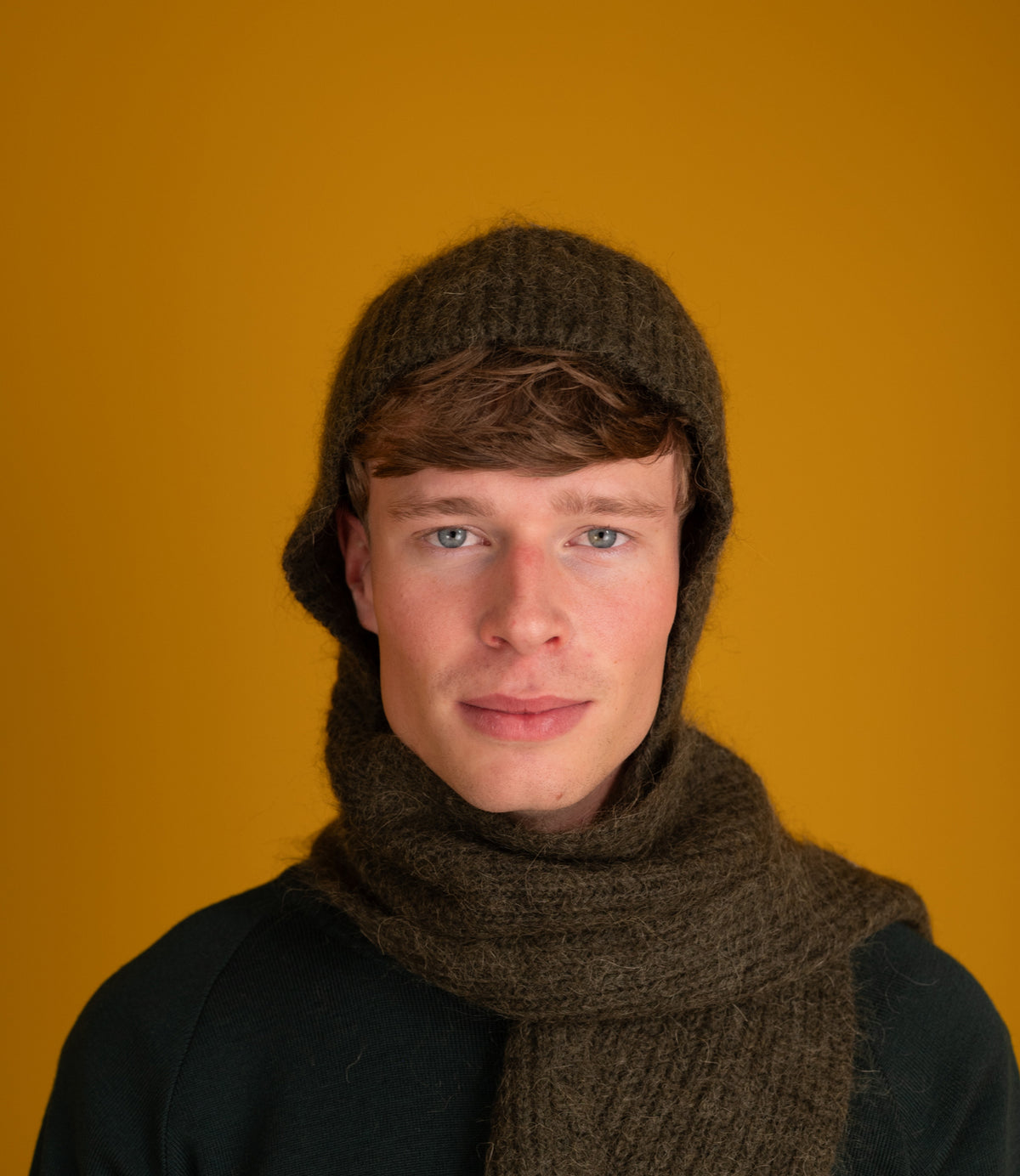 Model wearing the Bisa Hooded Scarf in sage with the hood up and scarf around the neck