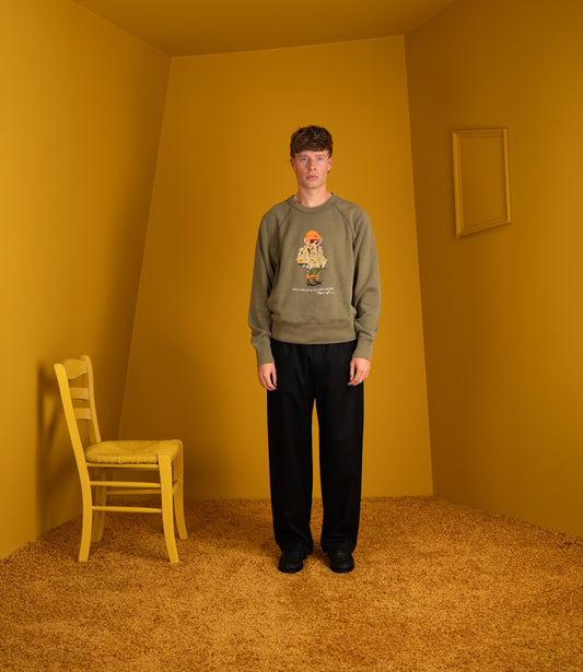Model wearing the Polo Ralph Lauren Polo Bear sweatshirt in cruise olive with black trousers