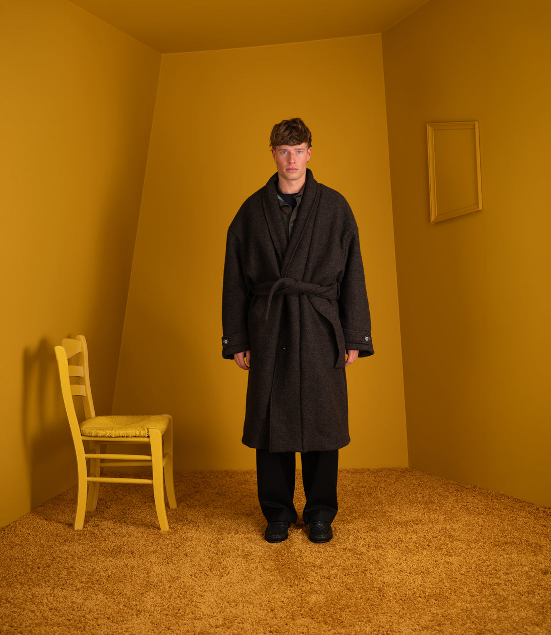 Model wearing the dark oak loden Jaca Coat belted with black trousers