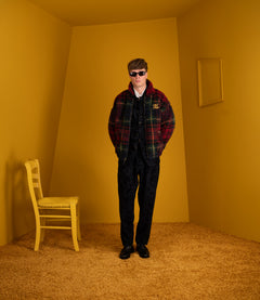 Model wearing the Polo Ralph Lauren holiday plaid fleece jacket with sunglasses and dark trousers