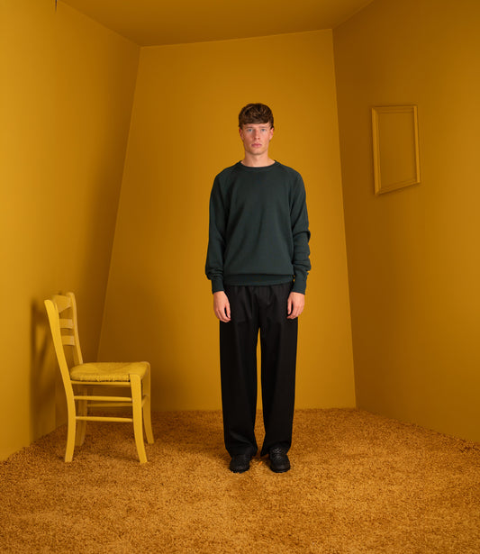 Model wearing the petrol Atelier Neighbourhood merino crewneck with black trousers